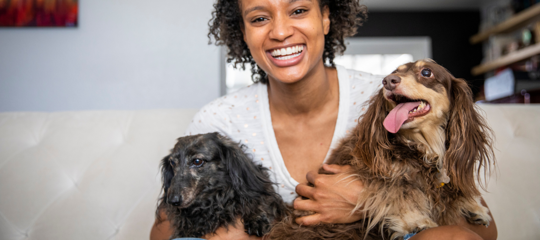 A woman holding two small dogs smiling